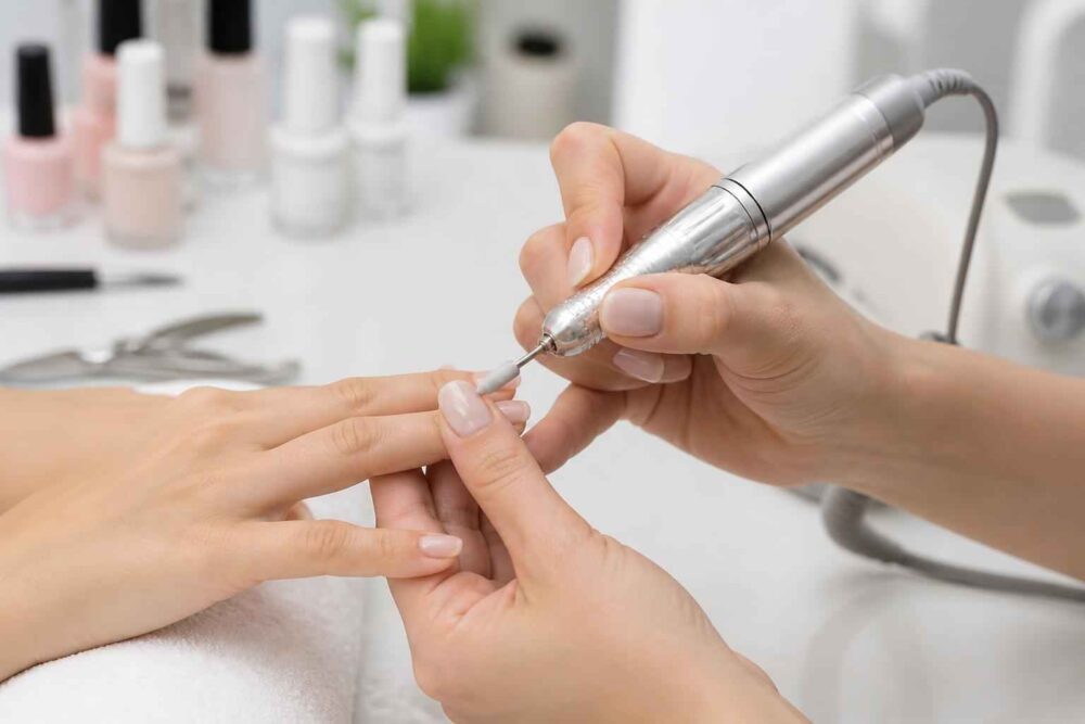 Stylistka opracowuje paznokieć frezarką podczas manicure hybrydowego
